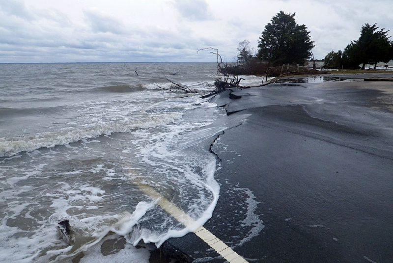 A parking lot being washed away by ocean waves during a storm.